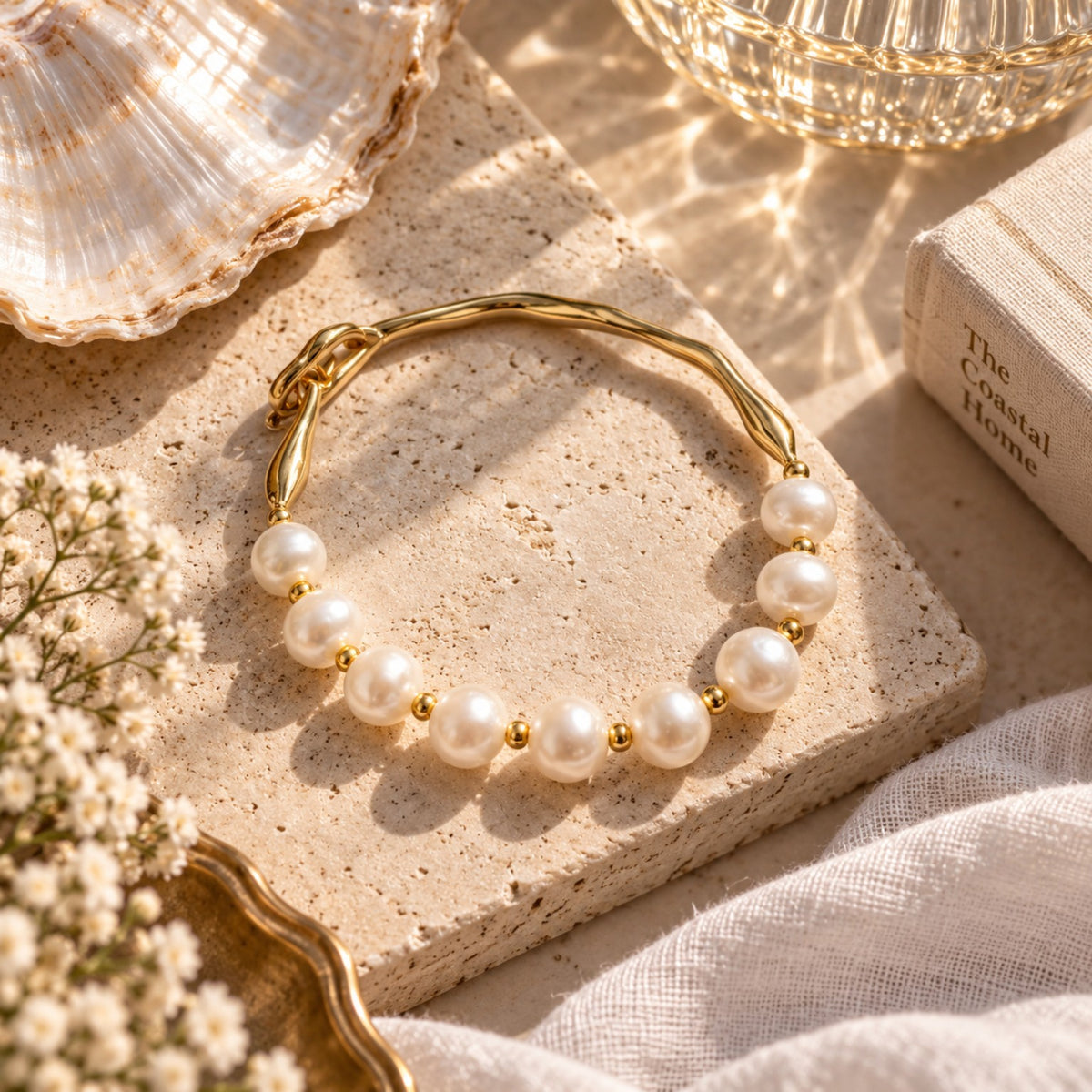 Gold and pearl bracelet styled in a coastal flat lay
